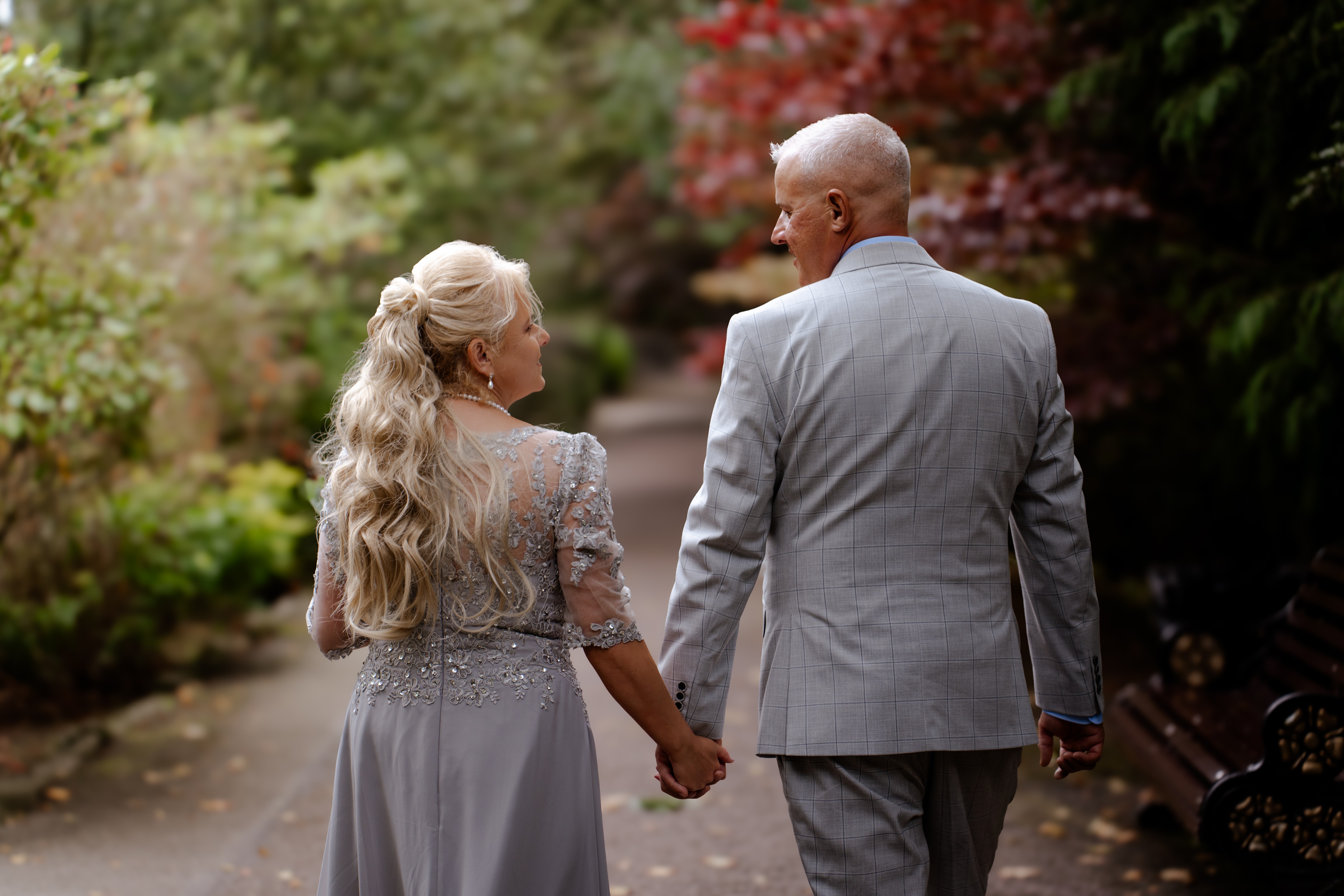 Couple walking hand in hand through a garden